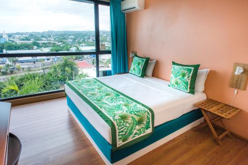 a bed in a room with a large window at Tahiti Airport Motel in Faaa