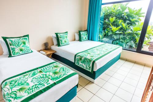 two beds in a room with a window at Tahiti Airport Motel in Faaa