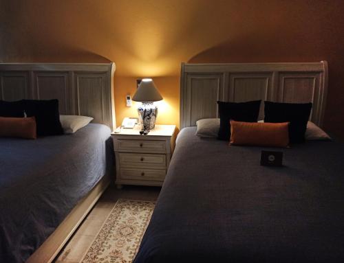 a bedroom with two beds and a lamp on a night stand at Hotel Boutique La Rioja in Atlixco