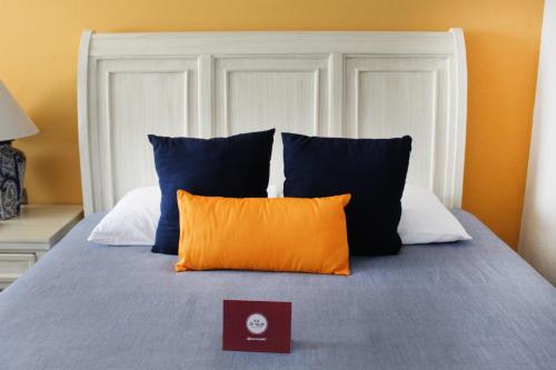 a bed with blue and orange pillows and a book at Hotel Boutique La Rioja in Atlixco