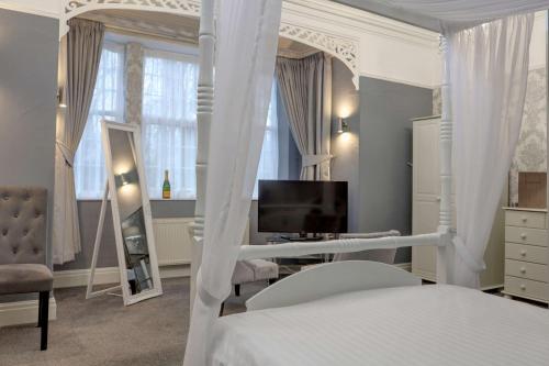 a bedroom with a white canopy bed and a television at Best Western Bolholt Country Park Hotel in Bury