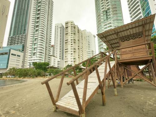 a wooden chair sitting on a beach with tall buildings at Casa Amanzi Cartagena by Bernalo Hotels in Cartagena de Indias