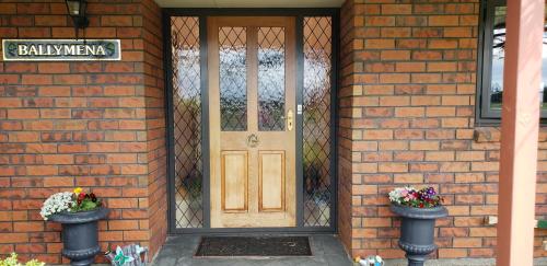 uma porta da frente de uma casa de tijolos com dois vasos de flores em Ballymena em Carterton