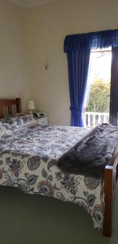 um quarto com uma cama com uma cortina azul e uma janela em Ballymena em Carterton