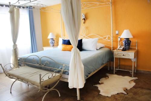 a bedroom with a canopy bed with a bench at Hotel Boutique La Rioja in Atlixco