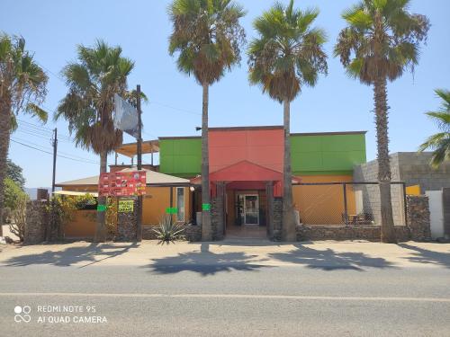 a building with palm trees in front of a street at La Vid Posada Inn in Valle de Guadalupe