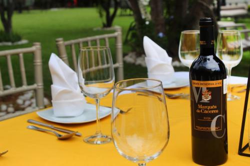 a bottle of wine sitting on a table with glasses at Hotel Boutique La Rioja in Atlixco
