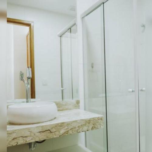 a white bathroom with a sink and a shower at Village AREIAS ITACIMIRIM - PÉ NA AREIA in Itacimirim