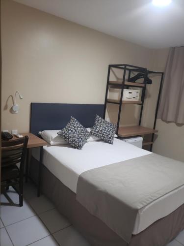 a bedroom with a bed with a desk and a chair at Villa Park Hotel Fortaleza in Fortaleza