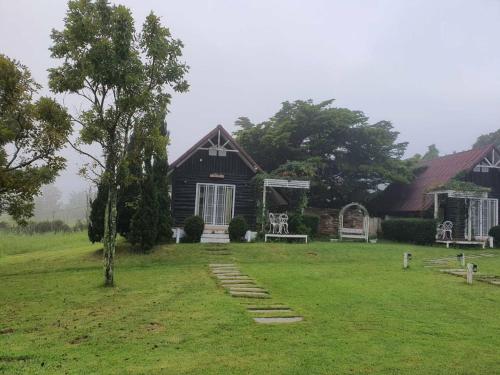a black house with a pathway in front of it at ไอหมอก ชาเล่ต์ in Wang Nam Khieo