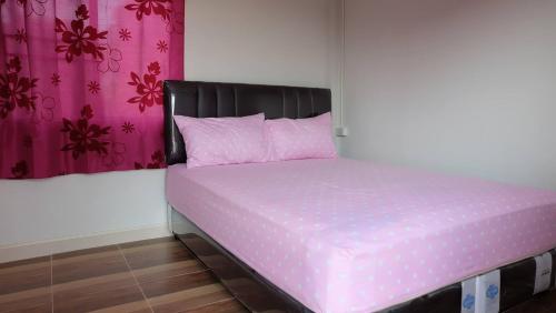 ein rosa Bett mit schwarzem Kopfteil in einem Zimmer in der Unterkunft Nakhonyok Homestay in Nakhon Nayok
