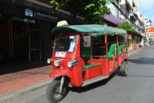 a red and green scooter driving down a street at Hotel Royal Bangkok in Bangkok