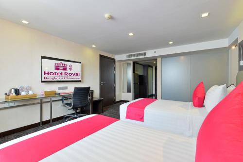 a hotel room with two beds and a desk at Hotel Royal Bangkok in Bangkok