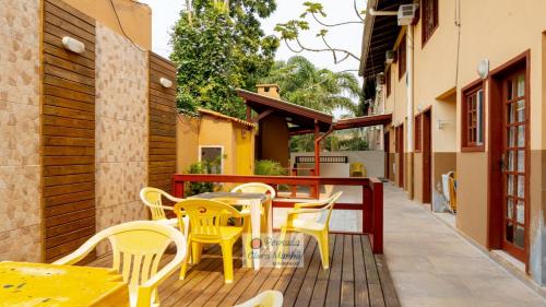a patio with yellow tables and chairs on a deck at Pousada Clara Manhã in Bombinhas