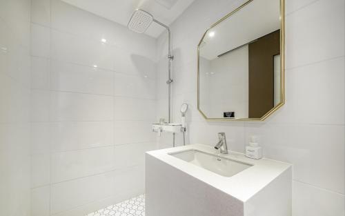 a white bathroom with a sink and a mirror at GijangYeonhwari No,25 Hotel in Busan