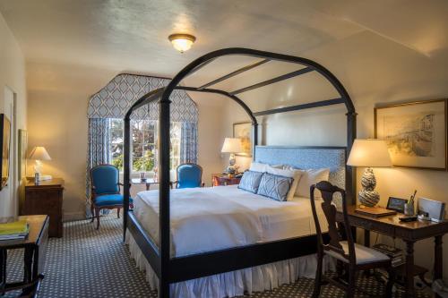 a bedroom with a large bed and a desk and chairs at L'Auberge Carmel, Relais & Chateaux in Carmel