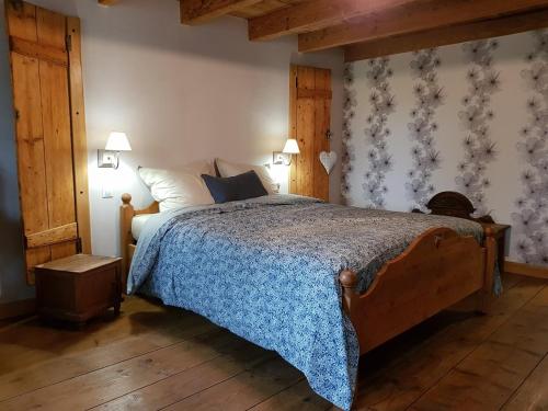 - une chambre avec un grand lit et une couverture bleue dans l'établissement Le jardin des gouttes, à Rougegoutte