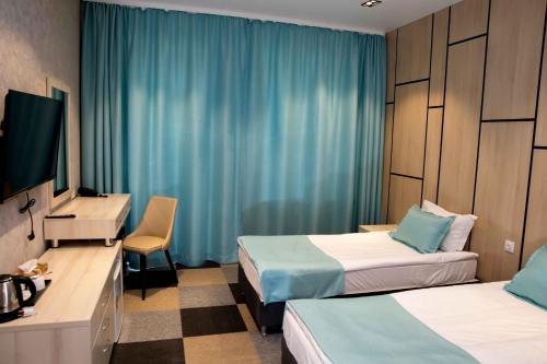 a hotel room with two beds and a television at Гостиничный комплекс Be Fine in Besqaynar