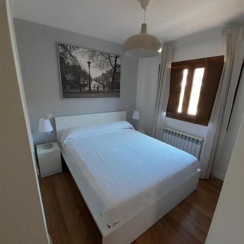 1 dormitorio con cama blanca y ventana en El Refugio del Tiétar, en La Adrada