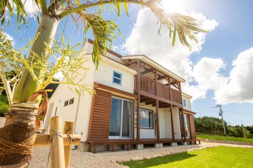 a house with a palm tree in front of it at UmiToSora Ishigakijima in Ishigaki Island