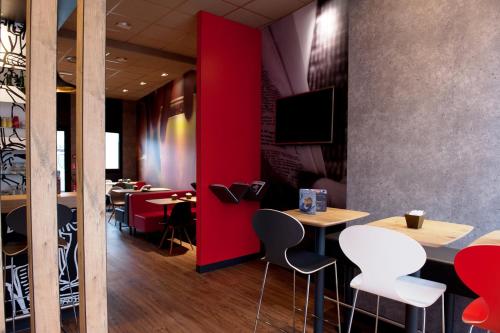 a restaurant with red walls and tables and chairs at Ibis Agen Centre Gare in Agen