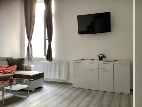 a living room with a couch and a tv on a wall at Belvárosi Apartman 1 in Miskolc