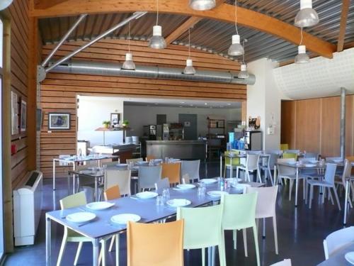 a dining room with tables and chairs and a kitchen at Auberge de Jeunesse HI Grenoble in Échirolles