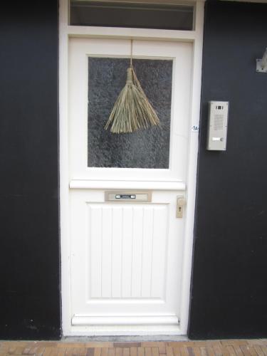 a white garage door with a broom on it at huisje de Strandjutter in Katwijk aan Zee