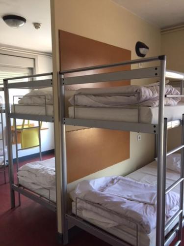 a bunk bed with three bunk beds in a room at Auberge de Jeunesse HI Grenoble in Échirolles