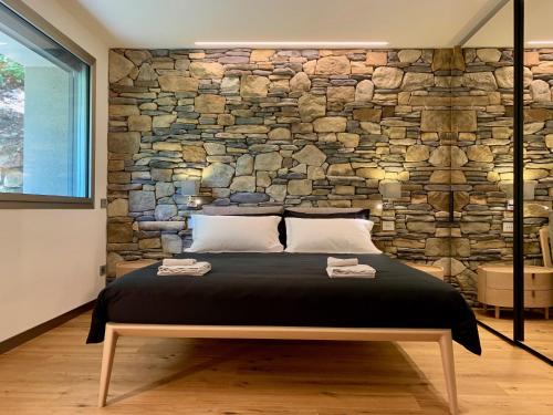 Un dormitorio con una pared de piedra y una cama en La Forestale Luxury Ecolodge B&B Primo Piano, en Acqualagna