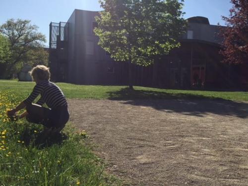 Un jeune garçon assis dans l'herbe avec un frisbee dans l'établissement Auberge de Jeunesse HI Grenoble, à Échirolles