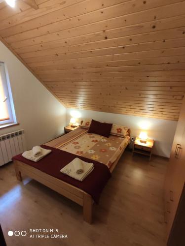 a bed in a room with a wooden ceiling at Domek u Lucy in Rabka