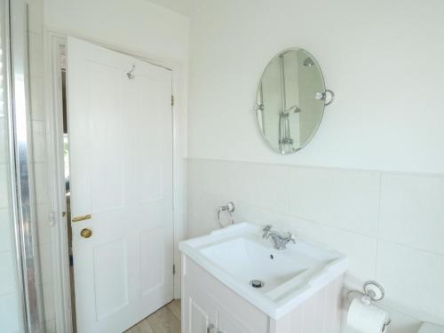 a white bathroom with a sink and a mirror at Elm Villa in Wareham