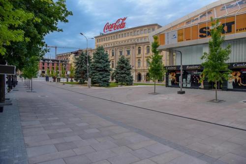 an empty street in a city with a cocacola building at Skopje City Square View in Skopje