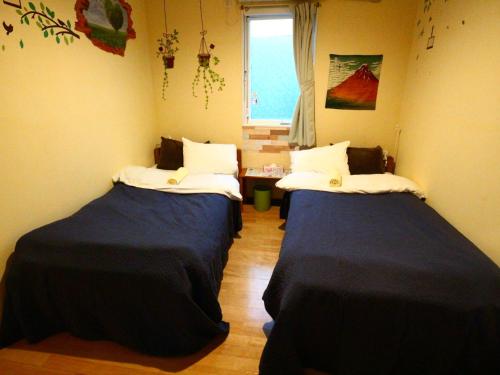 two beds in a small room with a window at ホステル富士山 結 in Fujiyoshida