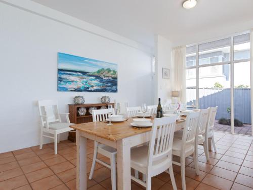 a dining room with a wooden table and white chairs at Corlette Waterfront 2 Waterfront Luxury WI FI Aircon Boat Parking in Corlette