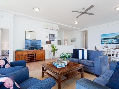 a living room with blue couches and a coffee table at Corlette Waterfront 2 Waterfront Luxury WI FI Aircon Boat Parking in Corlette