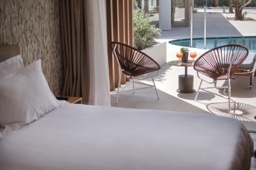 a bedroom with a bed and two chairs and a pool at Utopia Blu Hotel in Tigaki