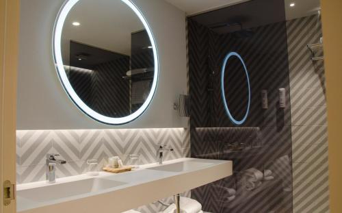 a bathroom with a mirror, sink, and bathtub at Suites Plaza Hotel & Wellness in Andorra la Vella