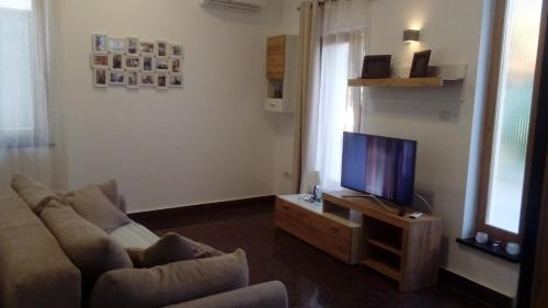 ein Wohnzimmer mit einem Sofa und einem TV in der Unterkunft Apartmani Belvedere in Novigrad Istria
