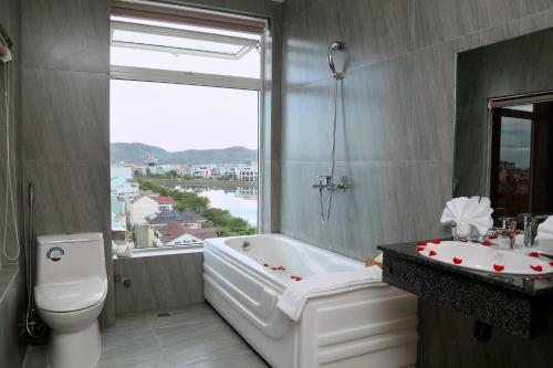 baño con bañera, aseo y ventana en Thanh Van Hotel Quy Nhon, en Quy Nhon