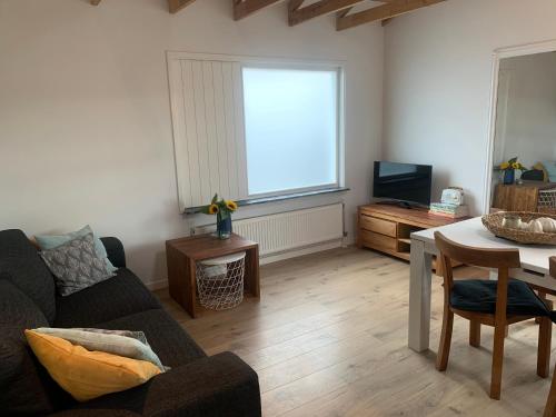 ein Wohnzimmer mit einem Sofa und einem Tisch in der Unterkunft Kust 1 in Egmond aan Zee