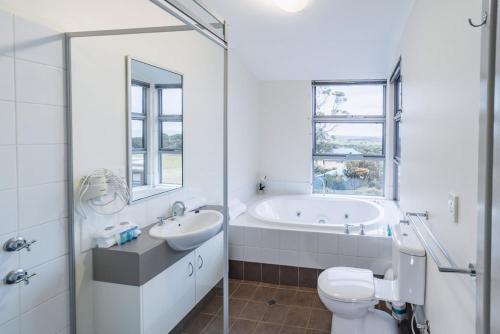 ein Badezimmer mit einer Badewanne, einem WC und einem Waschbecken in der Unterkunft Cosy Corner Sea View Apartments in Albany