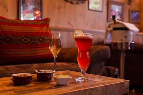 two drinks on a wooden table in a bar at Hôtel Macchi Restaurant & Spa in Châtel