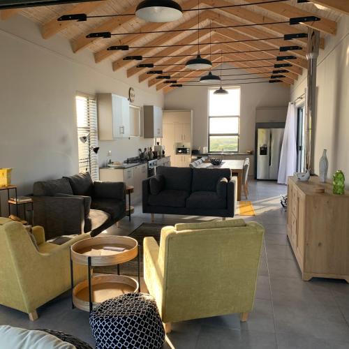 a living room with couches and chairs and a kitchen at Romansbaai at 402 - with solar power in Gansbaai