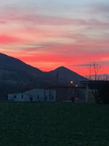 a sunset over a field with a mountain in the background at La Forestale Luxury Ecolodge B&B Primo Piano in Acqualagna
