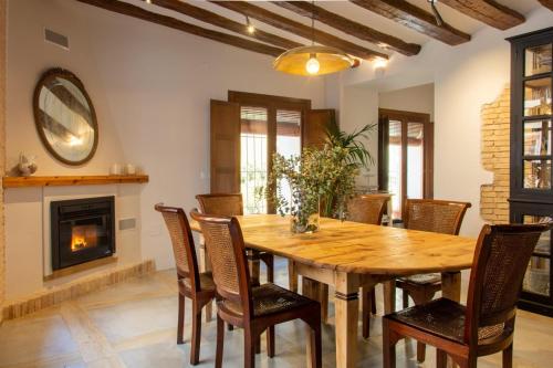 a dining room with a wooden table and chairs and a fireplace at Los Canilleros in Requena