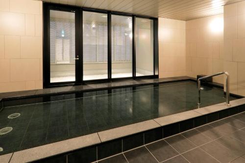 an empty swimming pool in a building with windows at JR Inn Sapporo Kita 2 Jo in Sapporo