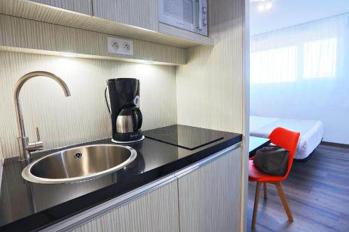uma cozinha com um lavatório e uma cadeira vermelha em Park Wilson Airport em Colomiers