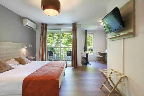 Cette chambre comprend un lit et une télévision à écran plat. dans l'établissement Odalys City Aix en Provence Le Clos de la Chartreuse, à Aix-en-Provence